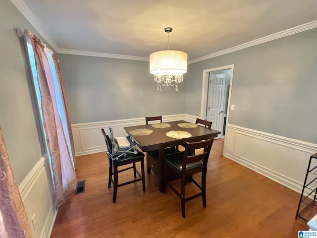 dining room with an inviting chandelier, hardwood / wood-style flooring, and crown molding