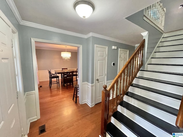 stairway with hardwood / wood-style floors, an inviting chandelier, and crown molding