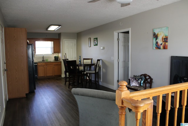 living room featuring a textured ceiling, ceiling fan, and dark hardwood / wood-style floors