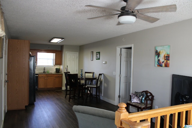 living room with a textured ceiling, ceiling fan, sink, and dark hardwood / wood-style floors