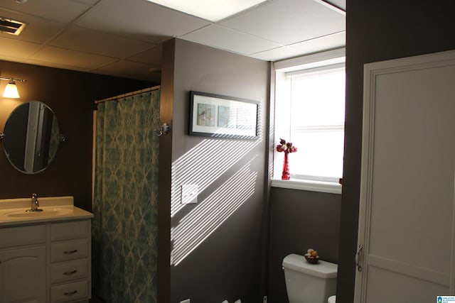 bathroom with toilet, vanity, and a drop ceiling