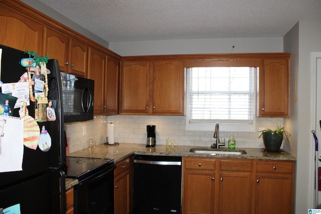 kitchen with sink, a textured ceiling, light stone counters, backsplash, and black appliances