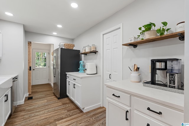 kitchen with white cabinetry, light hardwood / wood-style flooring, appliances with stainless steel finishes, and light stone countertops