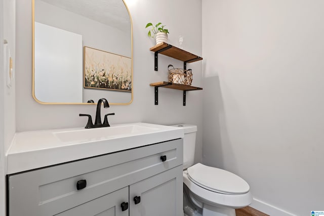 bathroom with toilet, vanity, and hardwood / wood-style flooring