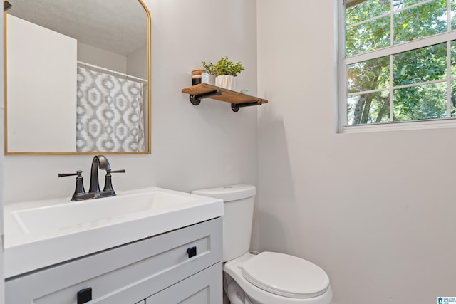 bathroom with toilet, vanity, and a textured ceiling