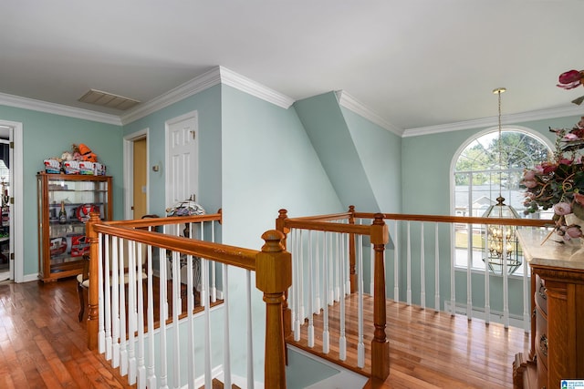 hall featuring wood-type flooring, crown molding, and an inviting chandelier