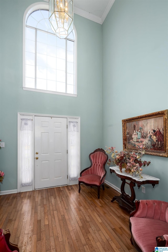 foyer featuring a chandelier, a towering ceiling, hardwood / wood-style flooring, and crown molding