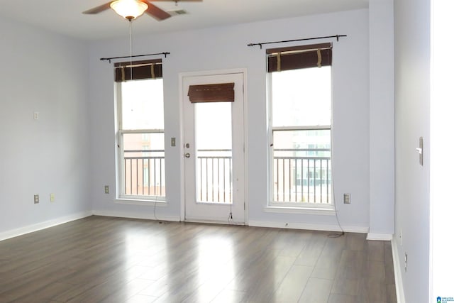 unfurnished room featuring ceiling fan, a wealth of natural light, and dark hardwood / wood-style floors