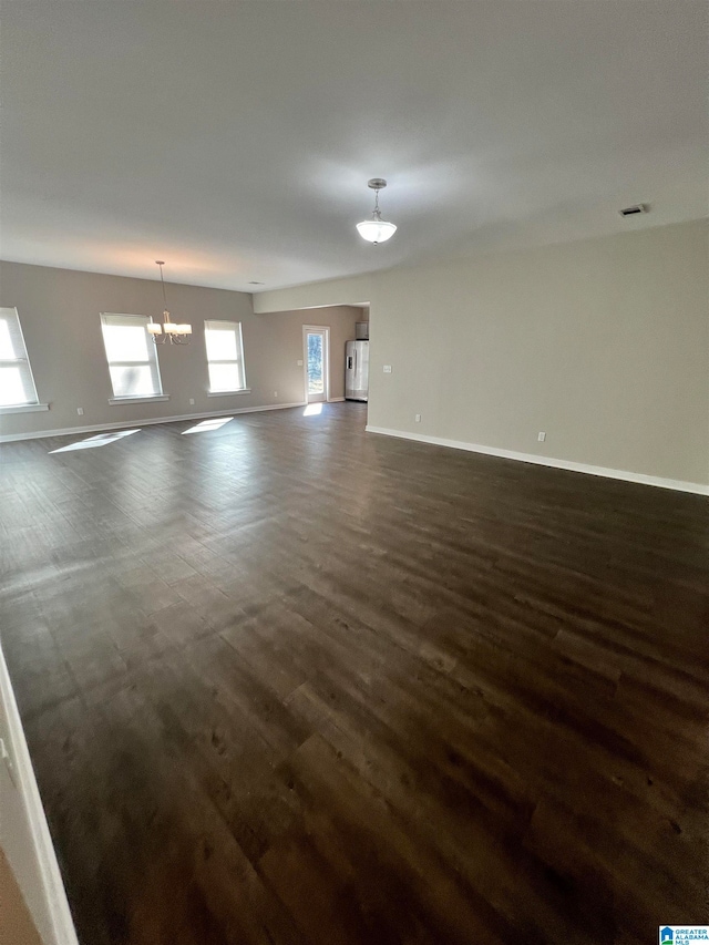 unfurnished living room with a chandelier and dark hardwood / wood-style floors