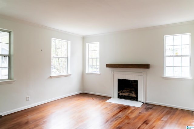 unfurnished living room featuring hardwood / wood-style flooring, ornamental molding, and plenty of natural light