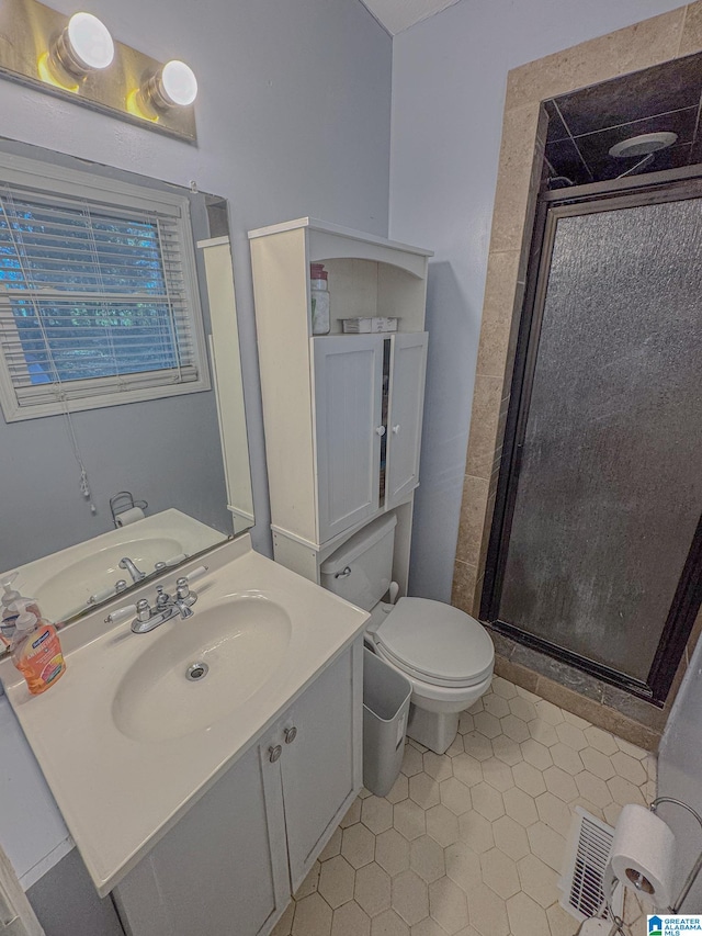 bathroom with tile patterned flooring, vanity, toilet, and a shower with shower door