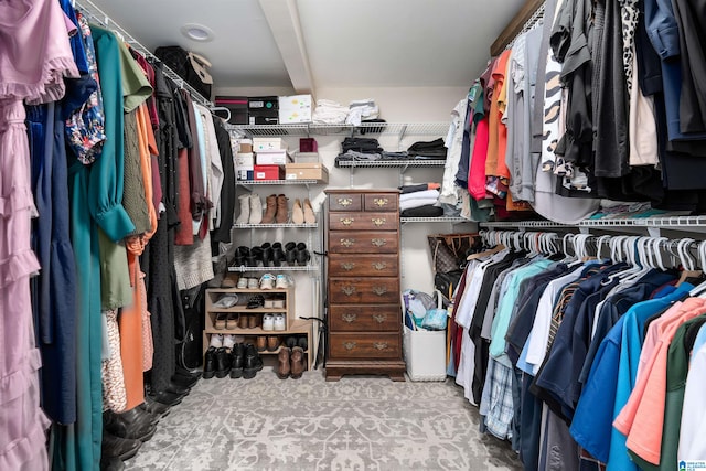 walk in closet featuring light colored carpet and beam ceiling