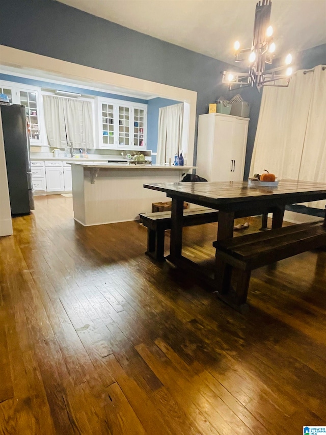 dining room featuring sink, dark wood-type flooring, and a notable chandelier