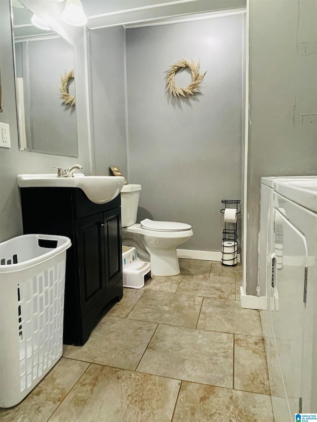 bathroom with tile patterned floors, washing machine and dryer, vanity, and toilet