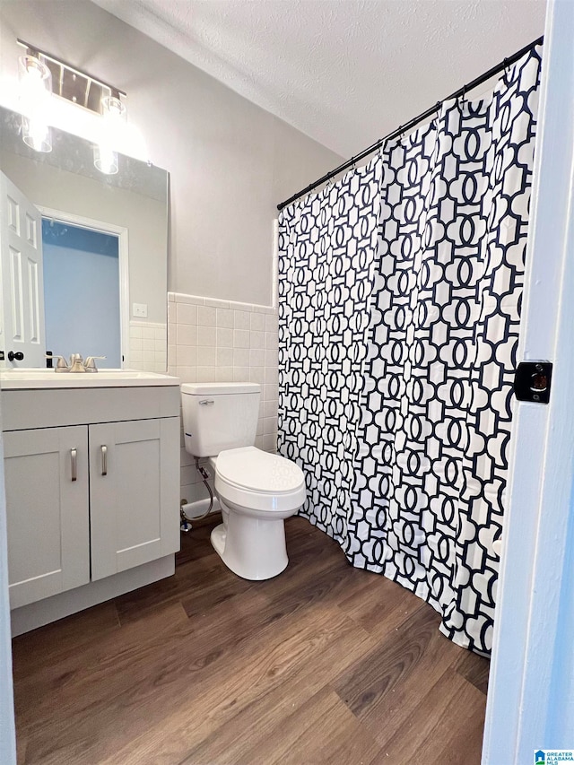 bathroom with wood-type flooring, toilet, tile walls, a textured ceiling, and vanity