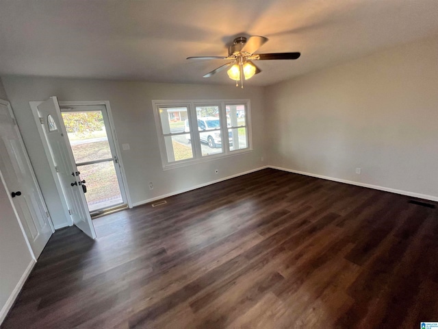 spare room featuring dark wood-type flooring, a wealth of natural light, and ceiling fan