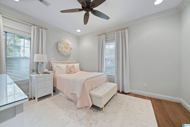 bedroom featuring ornamental molding, light wood-type flooring, multiple windows, and ceiling fan