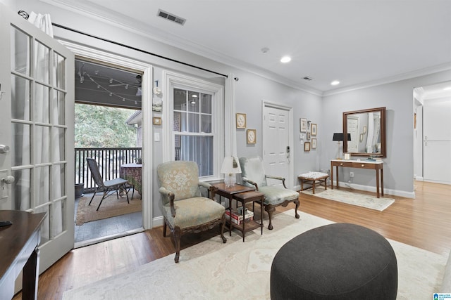 sitting room with light hardwood / wood-style flooring and ornamental molding