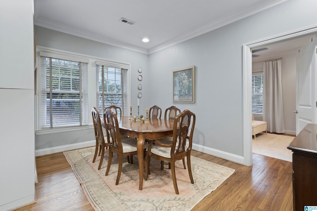 dining room with ornamental molding and light hardwood / wood-style flooring