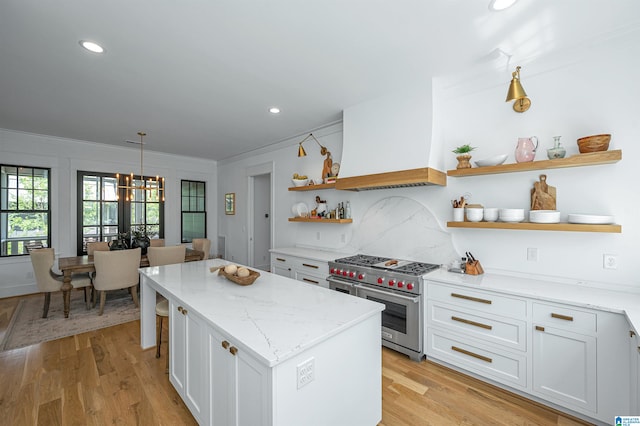 kitchen featuring a kitchen island, white cabinetry, custom exhaust hood, and designer range