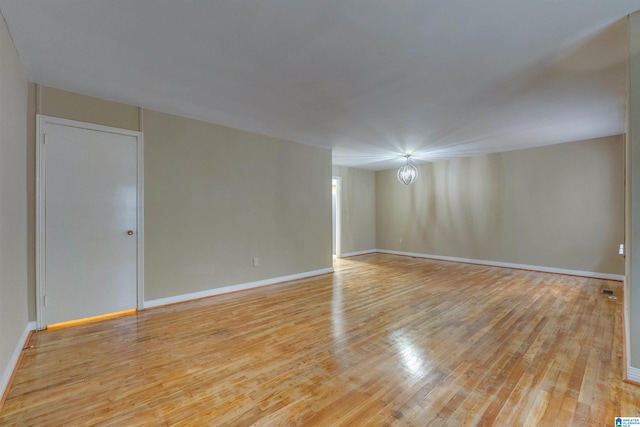 spare room with light hardwood / wood-style flooring and a notable chandelier