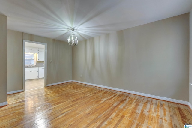 unfurnished room featuring sink, a notable chandelier, and light hardwood / wood-style floors