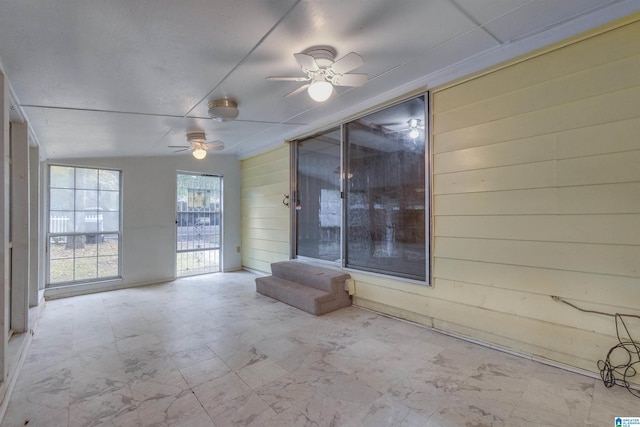 interior space with wood walls and ceiling fan