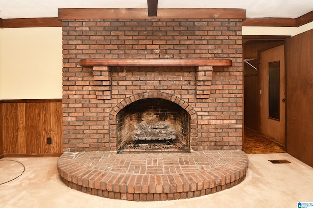 interior details featuring a brick fireplace, wooden walls, and carpet