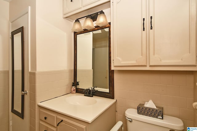 bathroom featuring toilet, vanity, and tile walls