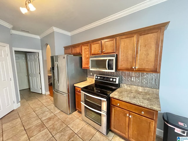 kitchen featuring light stone counters, ornamental molding, stainless steel appliances, backsplash, and light tile patterned floors