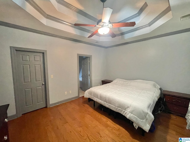 bedroom featuring ceiling fan, a raised ceiling, light hardwood / wood-style flooring, and ornamental molding