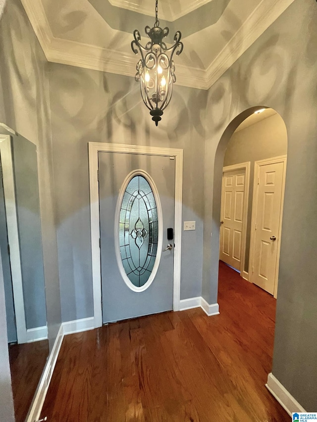 foyer featuring wood-type flooring, a raised ceiling, a chandelier, and crown molding