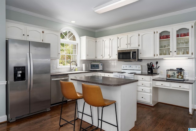 kitchen featuring stainless steel appliances, a kitchen island, sink, white cabinets, and dark wood-type flooring