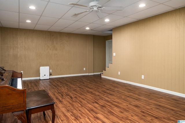 unfurnished room featuring a paneled ceiling, wooden walls, wood-type flooring, and ceiling fan