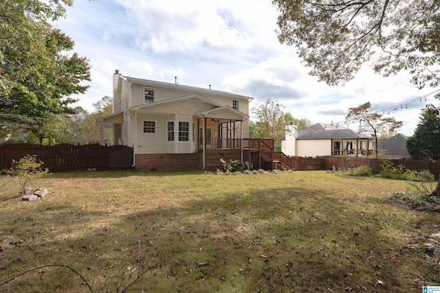 back of property featuring a wooden deck and a lawn