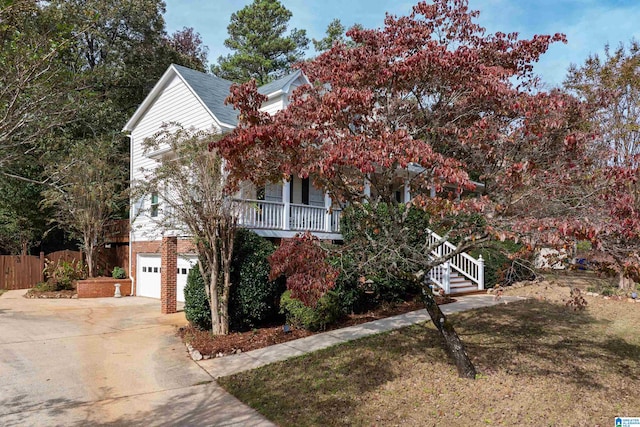 view of property hidden behind natural elements featuring a garage and covered porch