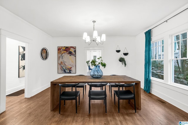 dining space with ornamental molding, dark wood-type flooring, and an inviting chandelier