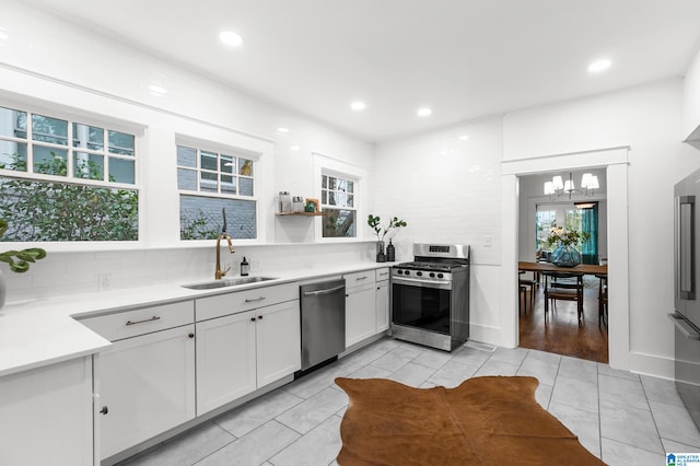 kitchen with stainless steel appliances, white cabinets, sink, and a healthy amount of sunlight