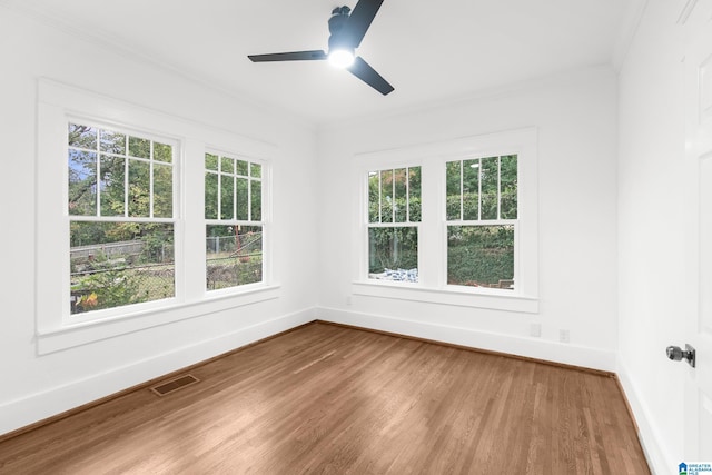 unfurnished room featuring hardwood / wood-style floors, ornamental molding, and plenty of natural light