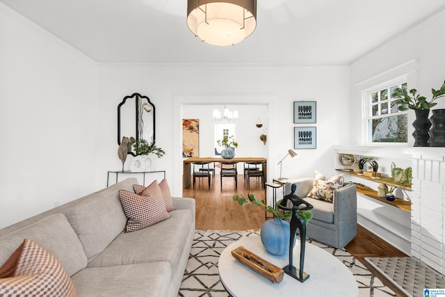 living room with wood-type flooring, a notable chandelier, and crown molding