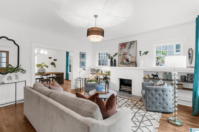 living room featuring hardwood / wood-style floors, crown molding, and a brick fireplace