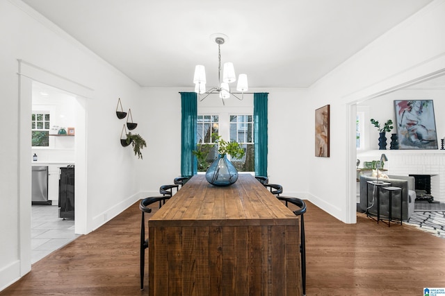 dining space with wood-type flooring, crown molding, and a notable chandelier