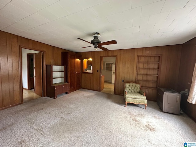 unfurnished room featuring ceiling fan, light colored carpet, and wooden walls