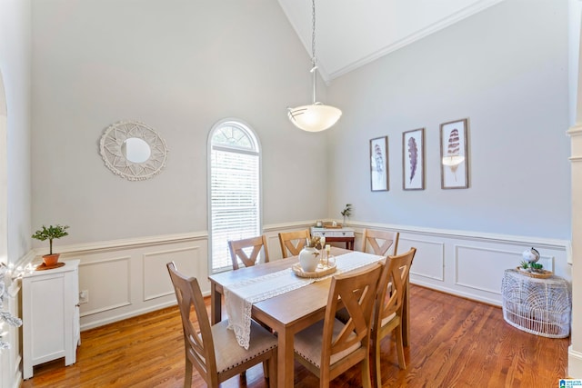 dining area with high vaulted ceiling, hardwood / wood-style floors, and ornamental molding