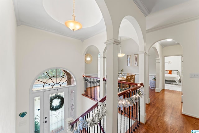 corridor featuring ornamental molding, wood-type flooring, and ornate columns