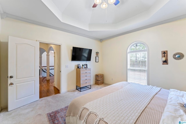 bedroom featuring ornamental molding, light carpet, ceiling fan, and a raised ceiling