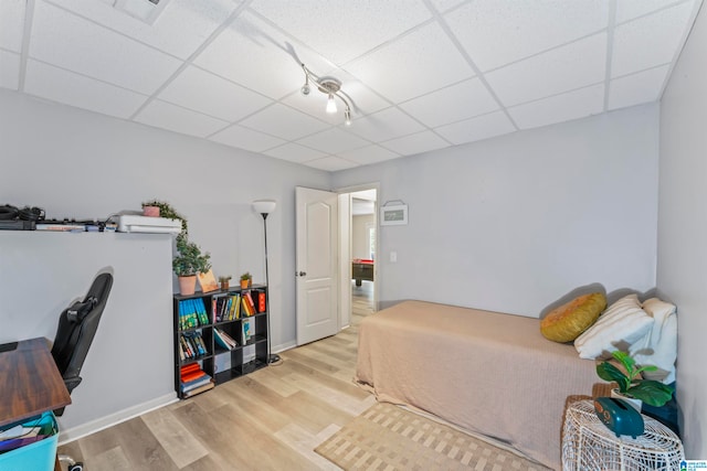 bedroom with light wood-type flooring and a drop ceiling