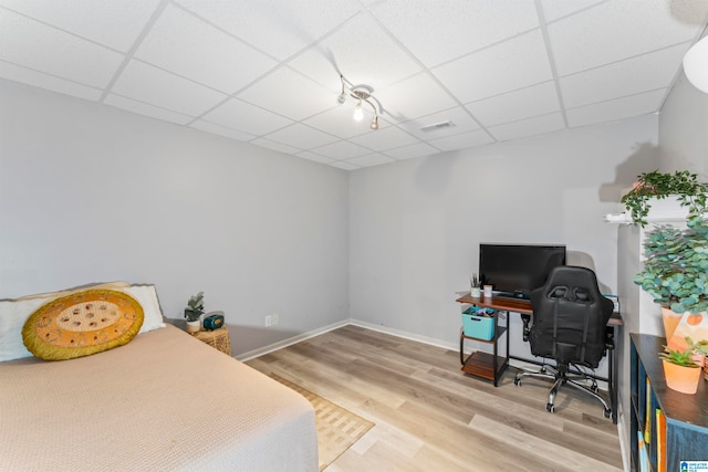 bedroom with a drop ceiling and hardwood / wood-style flooring