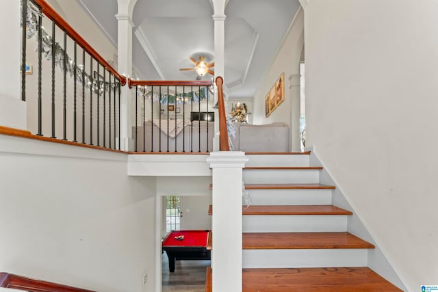 staircase featuring hardwood / wood-style floors, ceiling fan, crown molding, and decorative columns