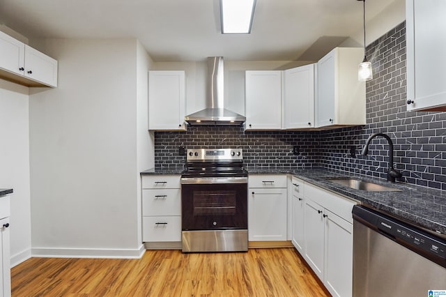 kitchen featuring light hardwood / wood-style floors, sink, appliances with stainless steel finishes, white cabinets, and wall chimney range hood